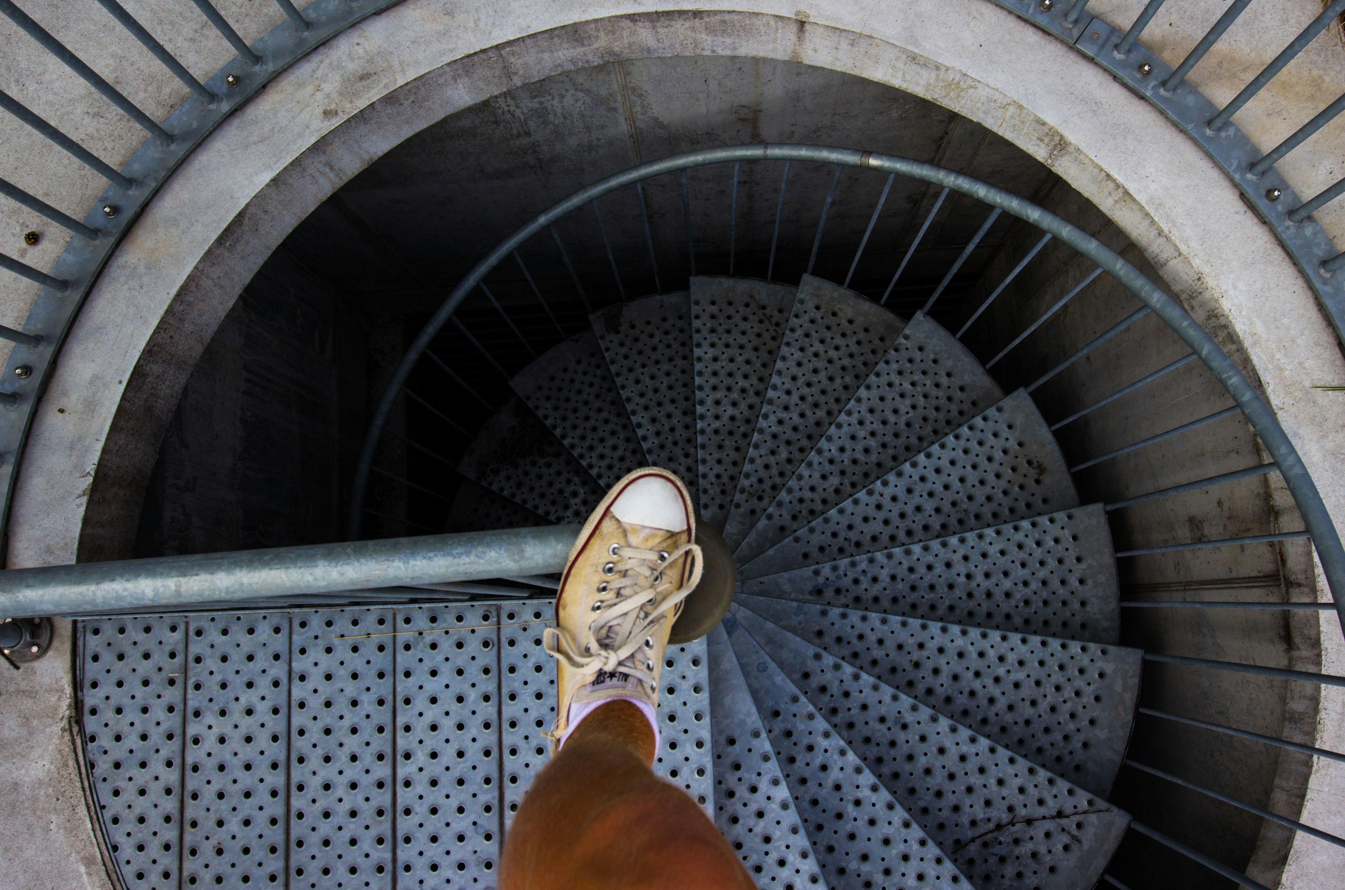 person in brown leather boots standing on spiral staircase